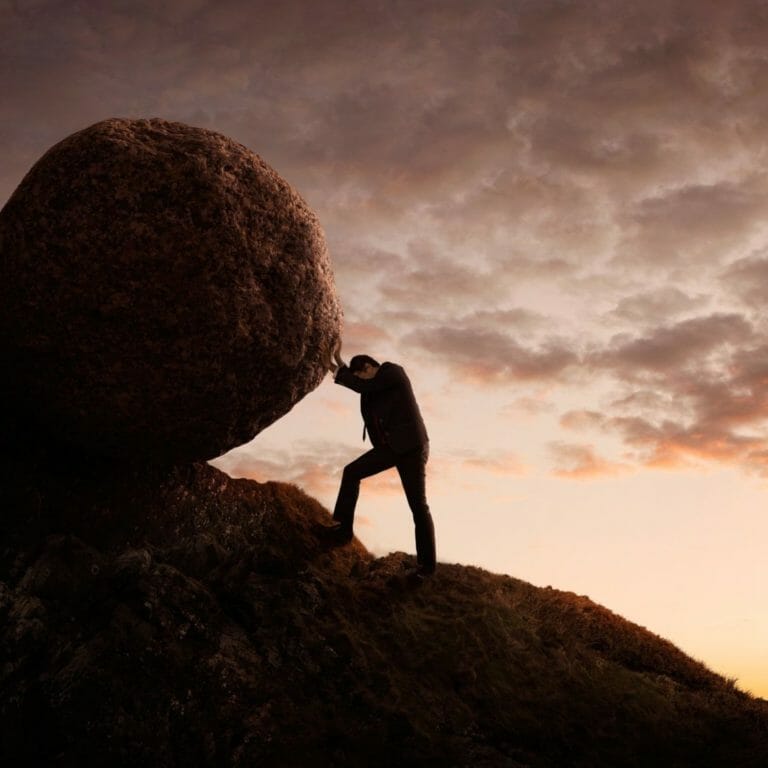 Man pushing boulder up mountain